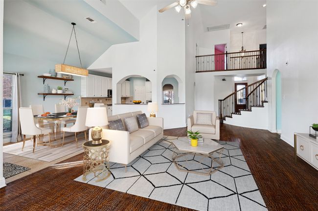 Living area with arched walkways, wood finished floors, visible vents, a ceiling fan, and stairway | Image 6