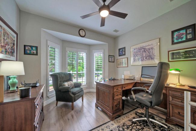 Home office with baseboards, light wood-type flooring, visible vents, and a ceiling fan | Image 26