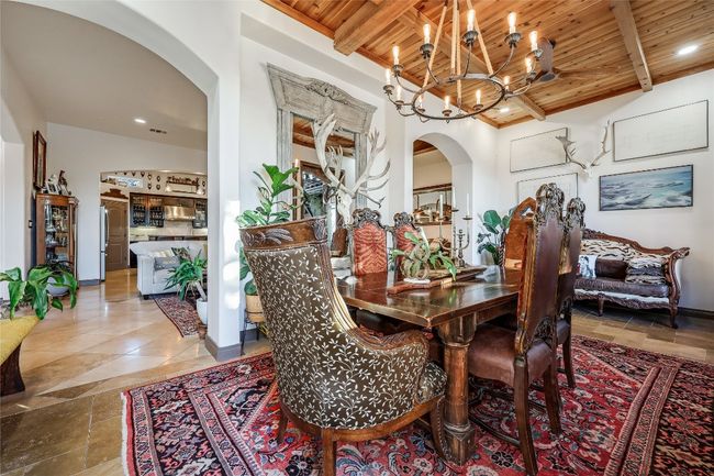 Dining space featuring arched walkways, a chandelier, wooden ceiling, and beam ceiling | Image 4