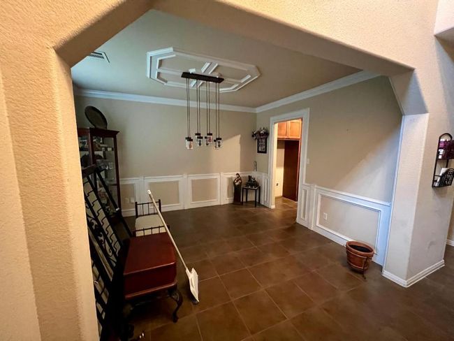 Unfurnished room with ornamental molding, a decorative wall, dark tile patterned floors, and a wainscoted wall | Image 4