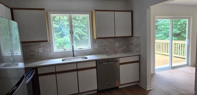 Kitchen featuring appliances with stainless steel finishes, white cabinets, light countertops, and wood finished floors | Image 6