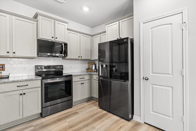 Kitchen with appliances with stainless steel finishes, light wood-style floors, tasteful backsplash, and light stone counters | Image 20