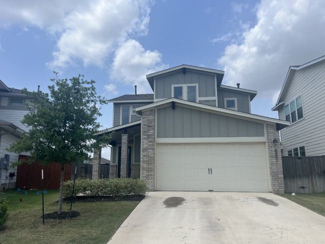 View of front of property featuring fence, an attached garage, brick siding, board and batten siding, and concrete driveway | Image 6