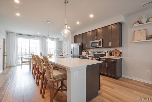 Kitchen featuring dark brown cabinets, stainless steel appliances, visible vents, and a sink | Image 8