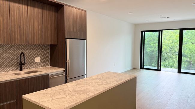 Kitchen with stainless steel appliances, modern cabinets, tasteful backsplash, light wood-style flooring, and a center island | Image 9