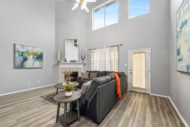 Living room with baseboards, a high ceiling, ceiling fan, wood finished floors, and a tile fireplace | Image 18