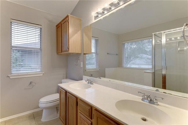 Unfurnished bedroom featuring a walk in closet, multiple windows, lofted ceiling, and light tile patterned floors | Image 12