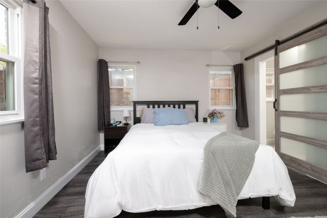 Bedroom featuring baseboards, a ceiling fan, a barn door, and dark wood-style floors | Image 25