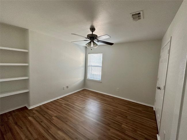 Unfurnished bedroom featuring a ceiling fan, wood finished floors, a textured ceiling, baseboards, and visible vents | Image 10