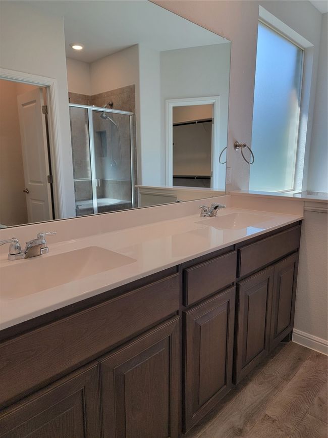 Bathroom featuring a shower stall, a walk in closet, double vanity, and wood finished floors | Image 15