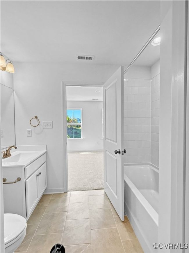 Bathroom with toilet, visible vents, shower / washtub combination, tile patterned flooring, and vanity | Image 4