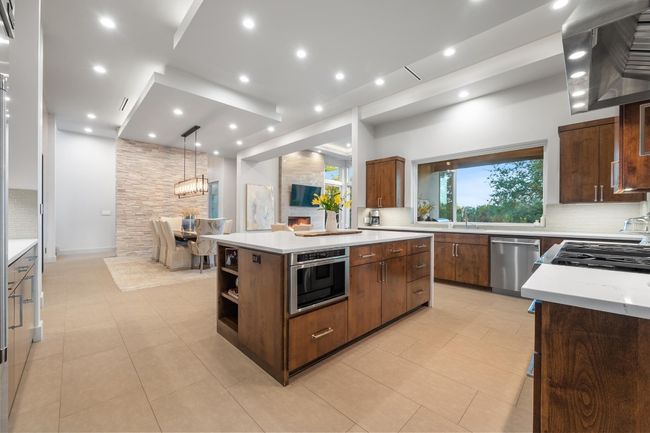 Kitchen featuring tasteful backsplash, light tile patterned floors, a center island, and stainless steel appliances | Image 9