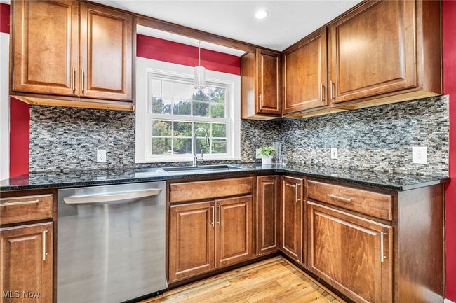 Kitchen featuring appliances with stainless steel finishes, a skylight, radiator heating unit, light wood flooring, and maple cabinetry | Image 9