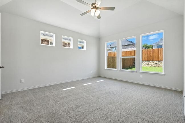 Carpeted empty room featuring ceiling fan and lofted ceiling | Image 16