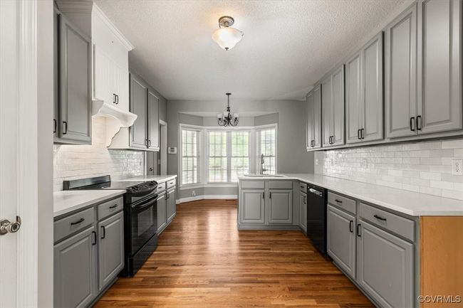 Kitchen featuring black appliances, gray cabinets, a peninsula, a sink, and a chandelier | Image 13