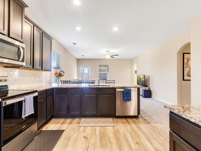 Kitchen with sink, dark brown cabinets, stainless steel appliances, light stone countertops, and decorative backsplash | Image 8