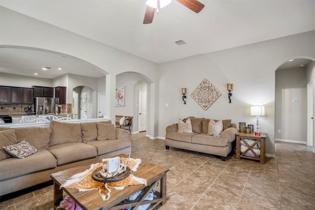 From the fireplace, you can see how the home opens up—dining and kitchen areas to the left, and both arched doorways ahead leading to separate bedroom hallways with a shared Jack-and-Jill bath in between. | Image 17