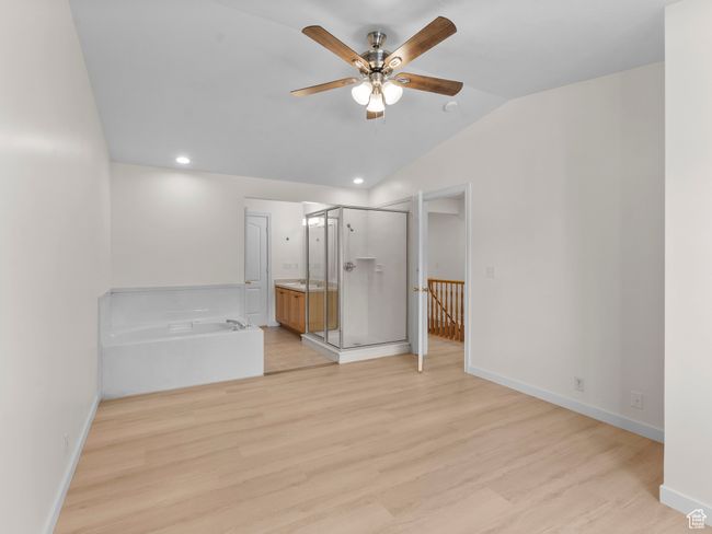 Unfurnished bedroom with light wood-style floors, vaulted ceiling, recessed lighting, connected bathroom, and ceiling fan | Image 18