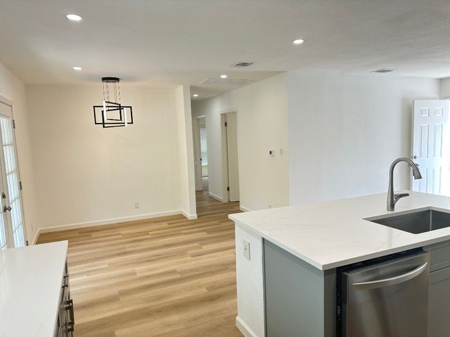 Kitchen with dishwasher, a sink, light wood-type flooring, recessed lighting, and light stone counters | Image 7
