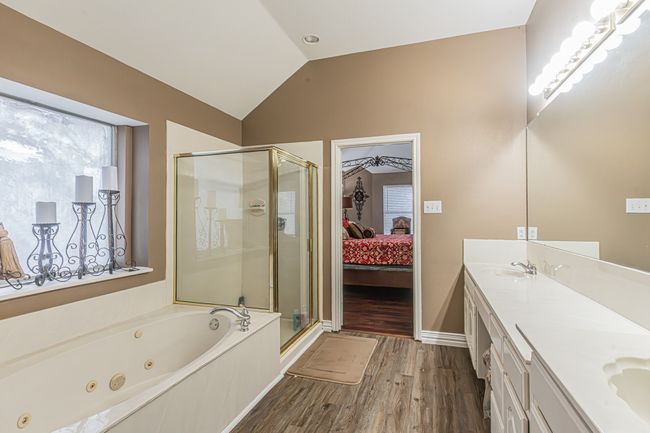 Ensuite bathroom with a stall shower, wood finished floors, a whirlpool tub, lofted ceiling, and double vanity | Image 23