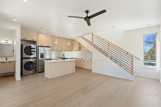Kitchen featuring modern cabinets, stainless steel refrigerator with ice dispenser, light brown cabinets, and stacked washer / drying machine | Image 25