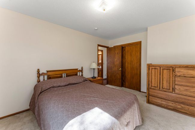 Across the hall, the second bedroom offers plush carpeting, natural light from front and side windows, and easy access to the shared full bathroom. | Image 11