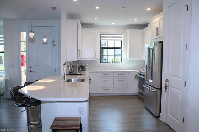 Kitchen with stainless steel appliances, dark wood-style floors, white cabinetry, and a peninsula | Image 5