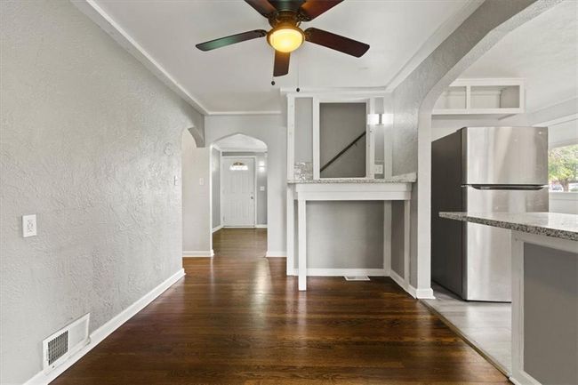 Unfurnished living room with a textured wall, arched walkways, wood finished floors, and ceiling fan | Image 8