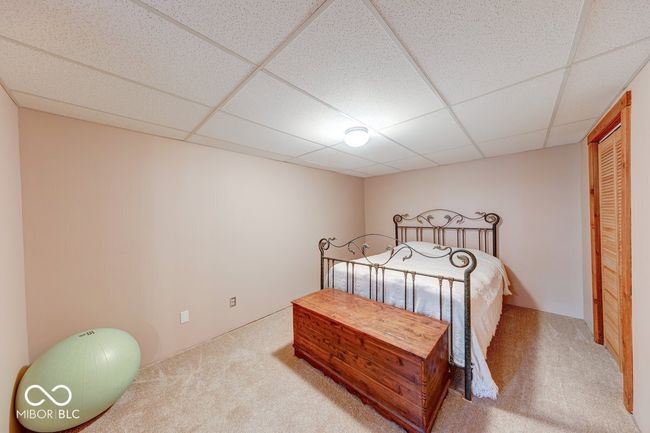 carpeted bedroom with a paneled ceiling | Image 16