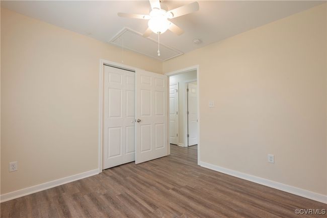 Unfurnished bedroom featuring a closet, baseboards, wood finished floors, a ceiling fan, and attic access | Image 21