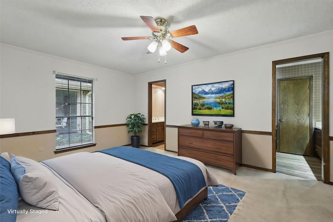 Virtually Staged Bedroom featuring light carpet, baseboards, a ceiling fan, connected bathroom, and ornamental molding | Image 23
