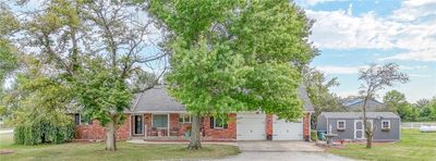 View of front facade featuring an outdoor structure, a garage, a porch, and a front lawn | Image 1