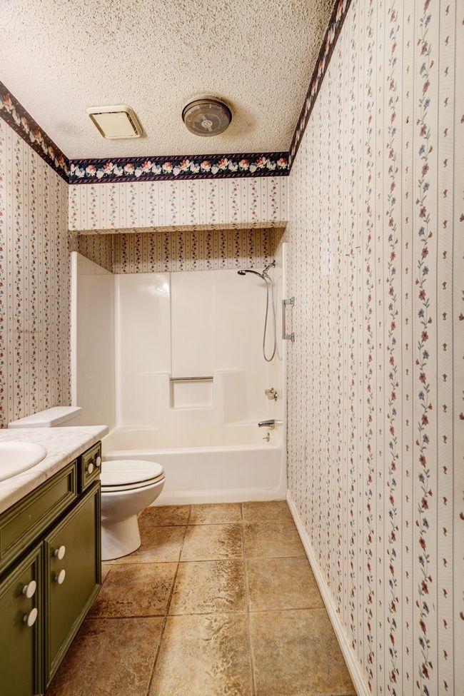 Bathroom featuring wallpapered walls, vanity, a textured ceiling, and bathing tub / shower combination | Image 15