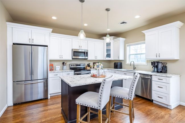 Kitchen with a sink, a breakfast bar area, white cabinets, appliances with stainless steel finishes, and visible vents | Image 10