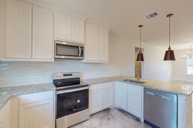 Kitchen with appliances with stainless steel finishes, a peninsula, tasteful backsplash, and decorative light fixtures | Image 14