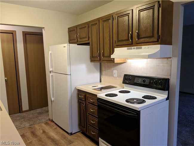 Kitchen with white appliances, light wood-type flooring, and tasteful backsplash | Image 15