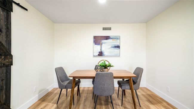 Dining area featuring a barn door, light wood finished floors, visible vents, and baseboards | Image 14