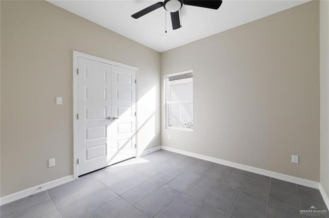 Unfurnished bedroom with dark tile patterned flooring, baseboards, and ceiling fan | Image 10