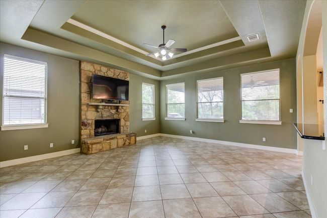Spacious living room with a tray ceiling, ceiling fan, and light tile patterned floors | Image 8