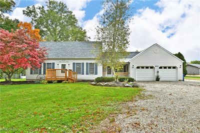 Conventional home featuring a front lawn, a wooden deck, and a garage & outbuilding | Image 1