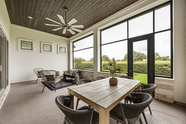 Sunroom with a ceiling fan, plenty of natural light, wood ceiling, and carpet flooring | Image 34