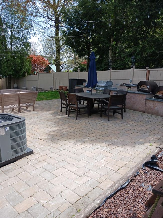 View of patio featuring cooling unit, outdoor dining space, a grill, and fence | Image 4