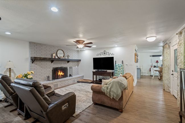 Living room featuring a brick fireplace, a ceiling fan, wood finished floors, and recessed lighting | Image 4