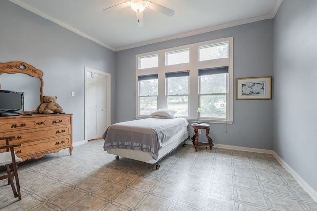 Bedroom within the primary suite, crown molding, ceiling fan, a closet, and light floors | Image 18