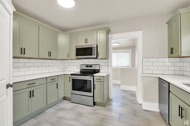 Kitchen with appliances with stainless steel finishes, green cabinets, light countertops, and tasteful backsplash | Image 11