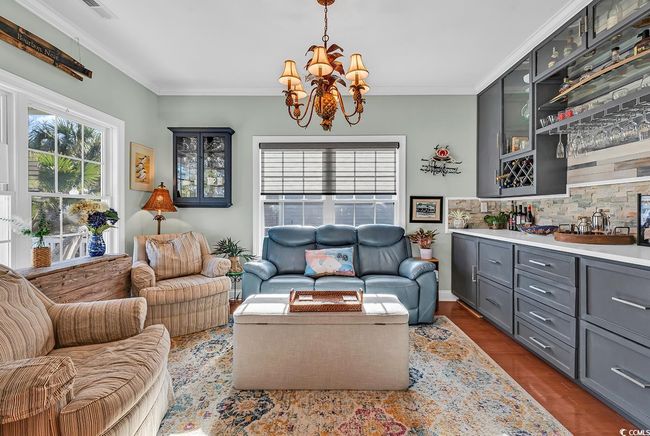 Living room with beverage cooler, a chandelier, ornamental molding, bar, and dark wood-type flooring | Image 5