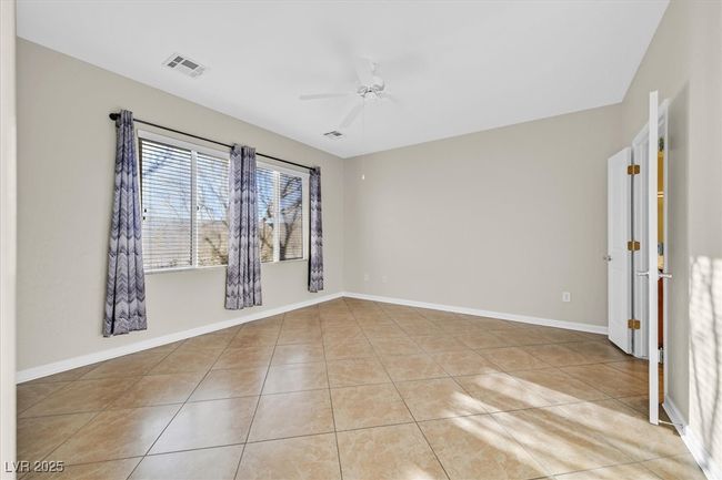 Primary bedroom with light tile patterned floors, baseboards, and a ceiling fan | Image 12