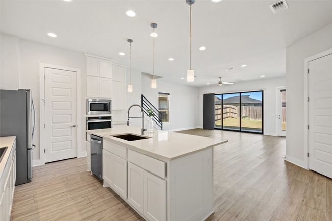 Kitchen with ceiling fan, stainless steel appliances, light wood-style floors, white cabinetry, and light countertops | Image 13