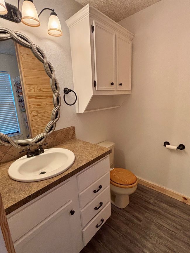 Bathroom with a textured ceiling, vanity, wood finished floors, and tasteful backsplash | Image 19