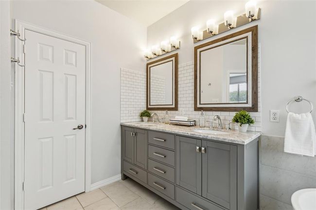 Bathroom featuring dual sinks, oversized vanity, backsplash, and tile floors | Image 17